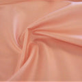 A swirled sample of luster soft foiled spandex in the color seashell-pink.