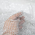 A hand pulling on a sample of Enigma Diamond Fishnet in the color White-Silver