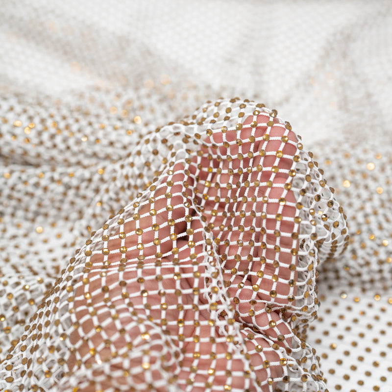 A hand pulling on a sample of Enigma Diamond Fishnet in the color White-Gold