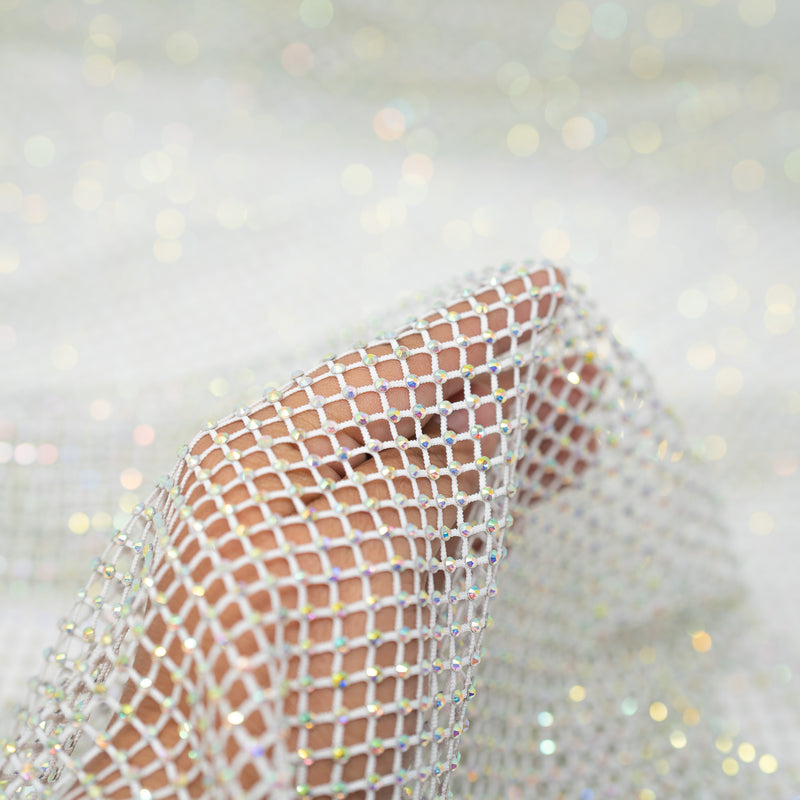 A hand pulling on a sample of Enigma Diamond Fishnet in the color White-Rainbow