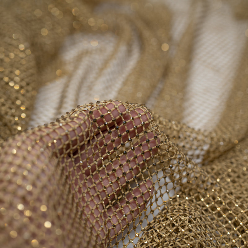 A hand pulling on a sample of Enigma Diamond Fishnet in the color Skin-Skin