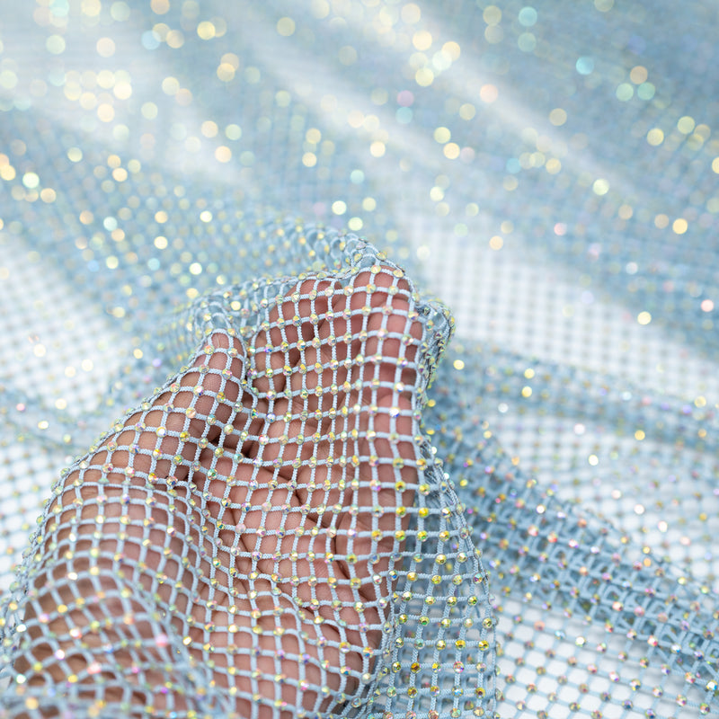 A hand pulling on a sample of Enigma Diamond Fishnet in the color Baby-Blue-Rainbow