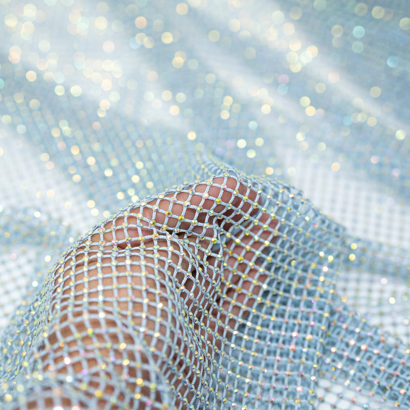 A hand pulling on a sample of Enigma Diamond Fishnet in the color Baby-Blue-Rainbow