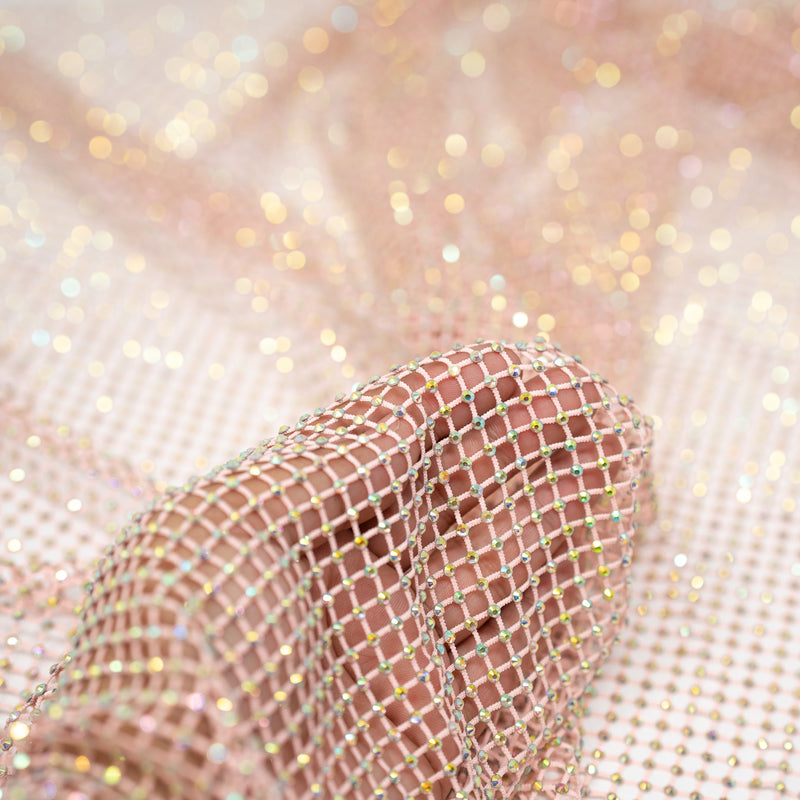 A hand pulling on a sample of Enigma Diamond Fishnet in the color Baby-Pink-Rainbow