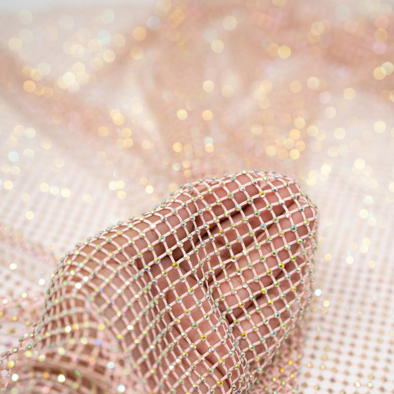 A hand pulling on a sample of Enigma Diamond Fishnet in the color Baby-Pink-Rainbow