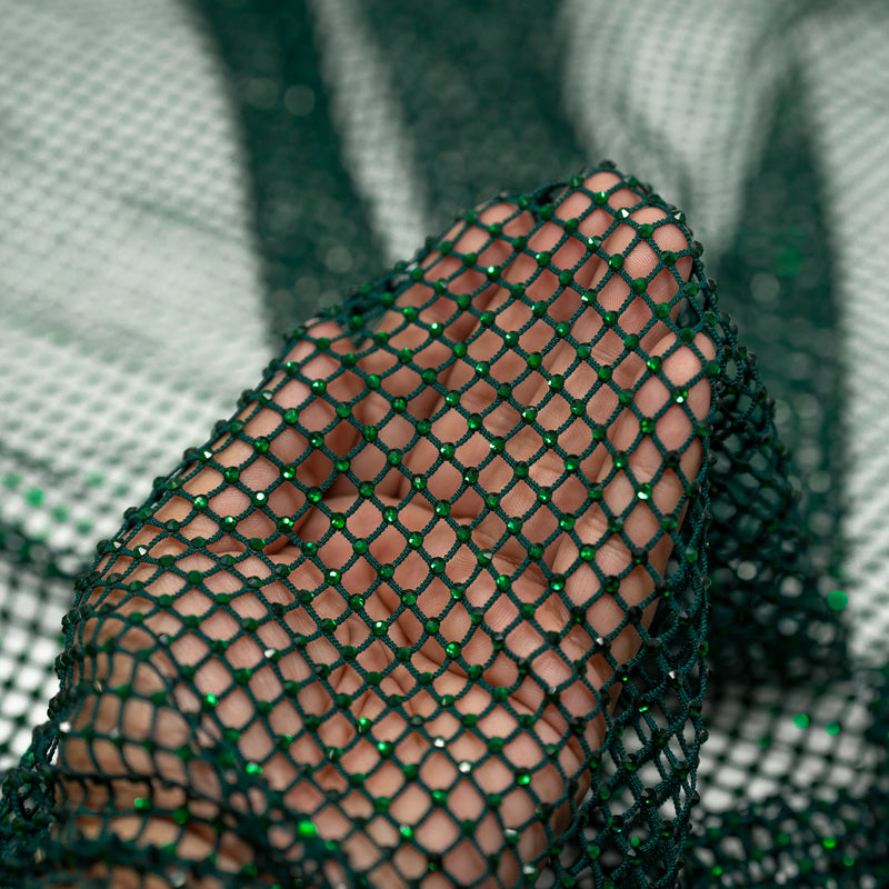 A hand pulling on a sample of Enigma Diamond Fishnet in the color Hunter-Green-Green