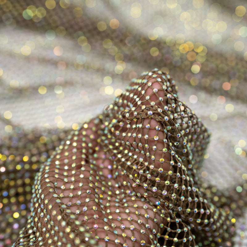A hand pulling on a sample of Enigma Diamond Fishnet in the color Brown-Rainbow