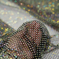 A hand pulling on a sample of Enigma Diamond Fishnet in the color Black-Rainbow