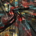 A swirled sample of madras foil printed stretch mesh in the color black-red-blue-gold.