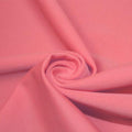 A swirled piece of matte nylon spandex fabric in the color blossom pink.