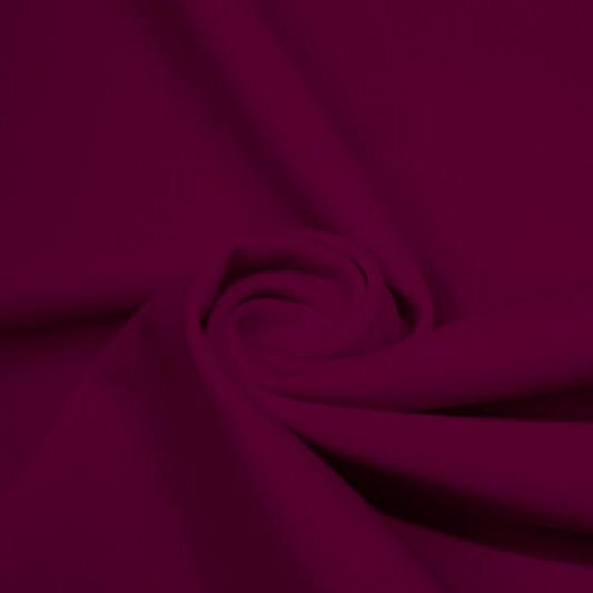 A swirled piece of matte nylon spandex fabric in the color dark berry.