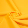 A swirled piece of matte nylon spandex fabric in the color halei yellow.