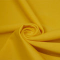 A swirled piece of matte nylon spandex fabric in the color havana yellow.