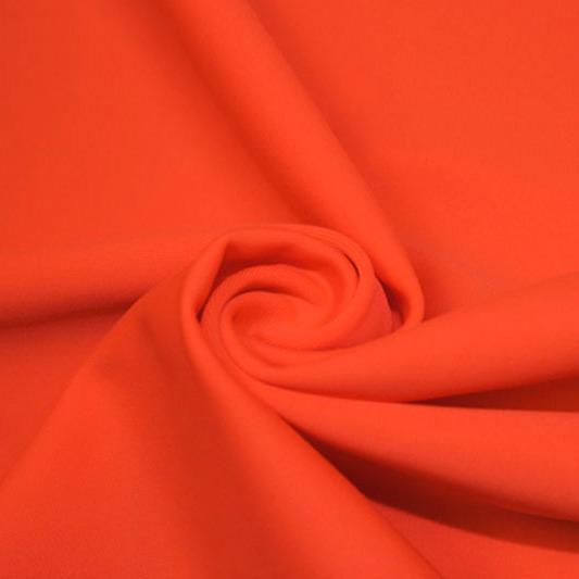 A swirled piece of matte nylon spandex fabric in the color hot coral.