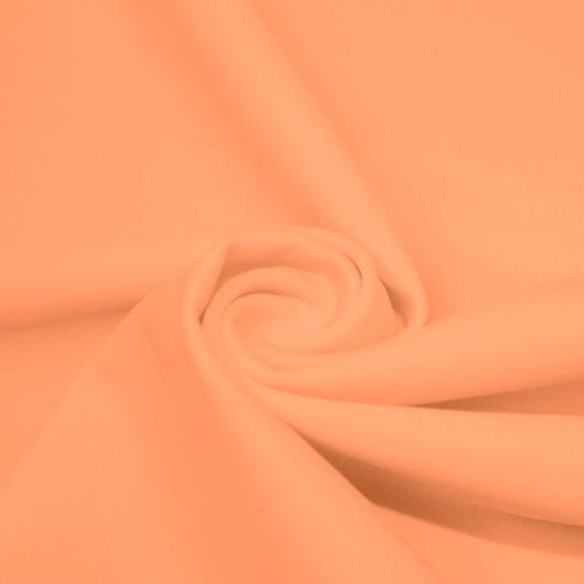 A swirled piece of matte nylon spandex fabric in the color peach.