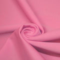A swirled piece of matte nylon spandex fabric in the color pink sorbet.