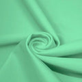 A swirled piece of matte nylon spandex fabric in the color sea foam.