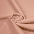 A swirled piece of matte nylon spandex fabric in the color sun beige.