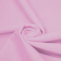 A swirled piece of matte nylon spandex fabric in the color venus pink.