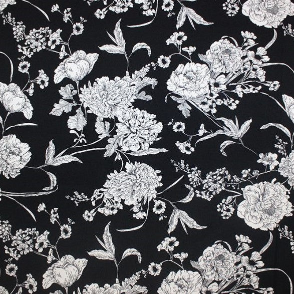A flat sample of white flowers on black printed spandex.