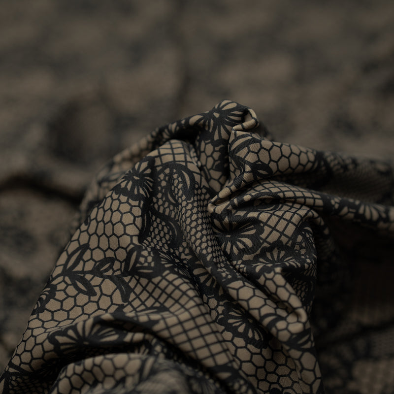 A crumpled piece of Black Illusion Lace Pattern on Brown Printed Spandex
