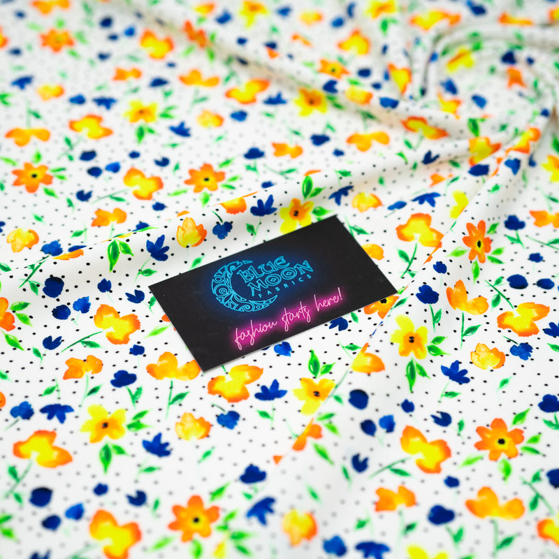 Swirled sample shot of Watercolor Flowers and Black Dots Printed Spandex with a Blue Moon Fabrics standard size business card laid on top of the print for pattern sizing.