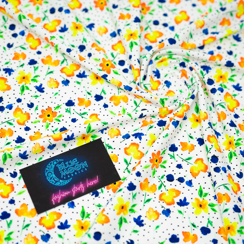 Swirled sample shot of Watercolor Flowers and Black Dots Printed Spandex with a Blue Moon Fabrics standard size business card laid on top of the print for pattern sizing.