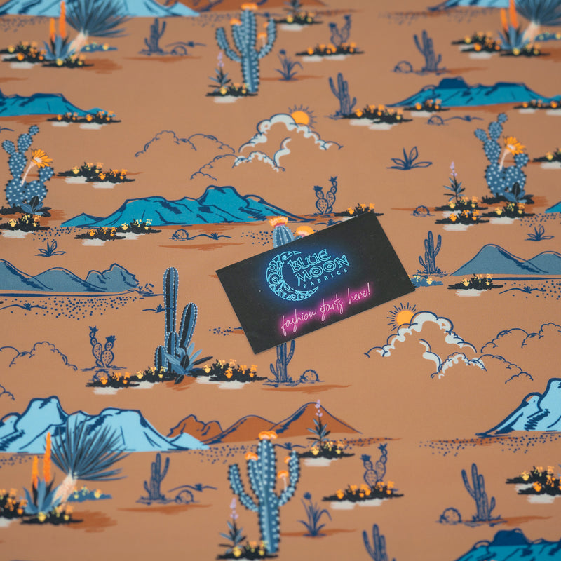 A flat sample of Western Desert Bloom Printed Spandex with a Blue Moon Fabrics standard size business card laid on top of the print for pattern sizing.
