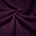 A swirled piece of shiny nylon spandex in the color aubergine.
