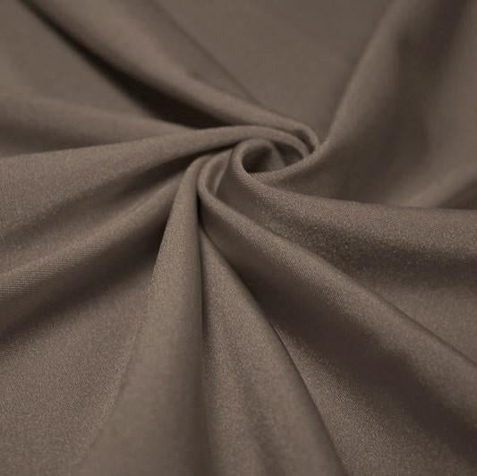 A swirled piece of shiny nylon spandex in the color dust.