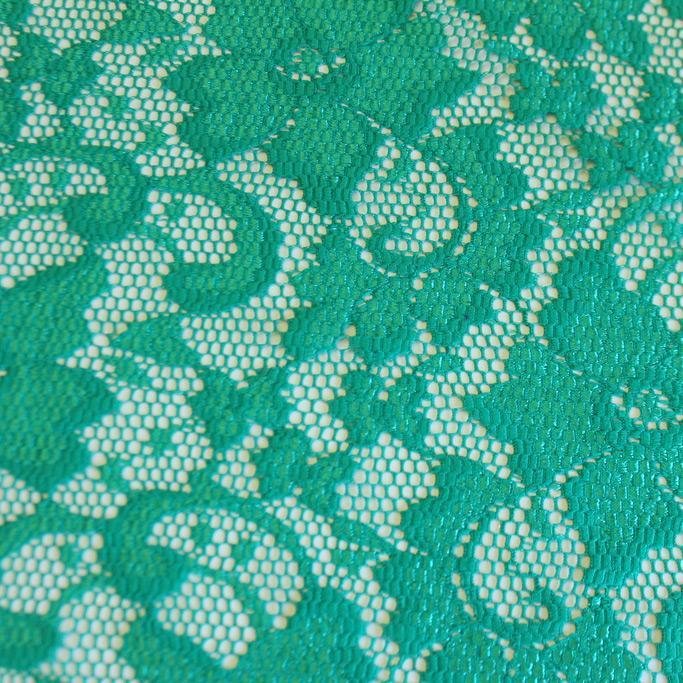 A flat sample of nadia scalloped stretch lace in the color jade blue.