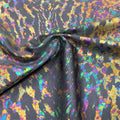 A swirled sample of naga foil printed spandex in the color charcoal/iridescent.