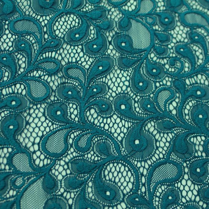 A falt sample of olivia stretch lace in the color teal blue.