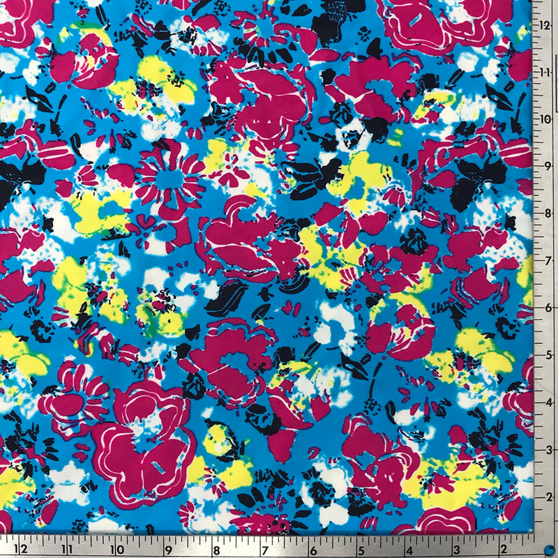 A flat sample of floral impressions printed spandex with a scale to measure the size of the design.