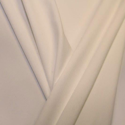 A pleated piece of performance nylon spandex fabric in the color candle light.