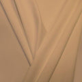 A pleated piece of performance nylon spandex fabric in the color honey beige.
