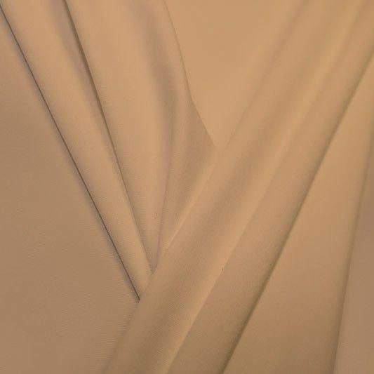 A pleated piece of performance nylon spandex fabric in the color honey beige.