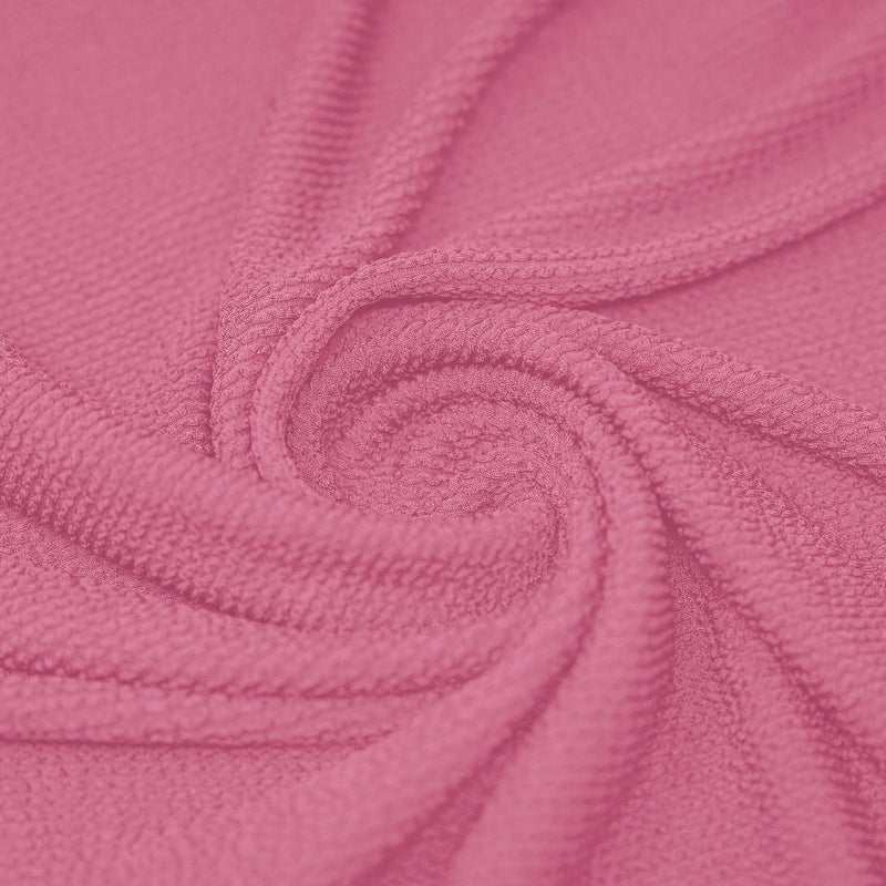 A swirled piece of crinkle polyester spandex jacquard fabric in the color Pink Sorbet