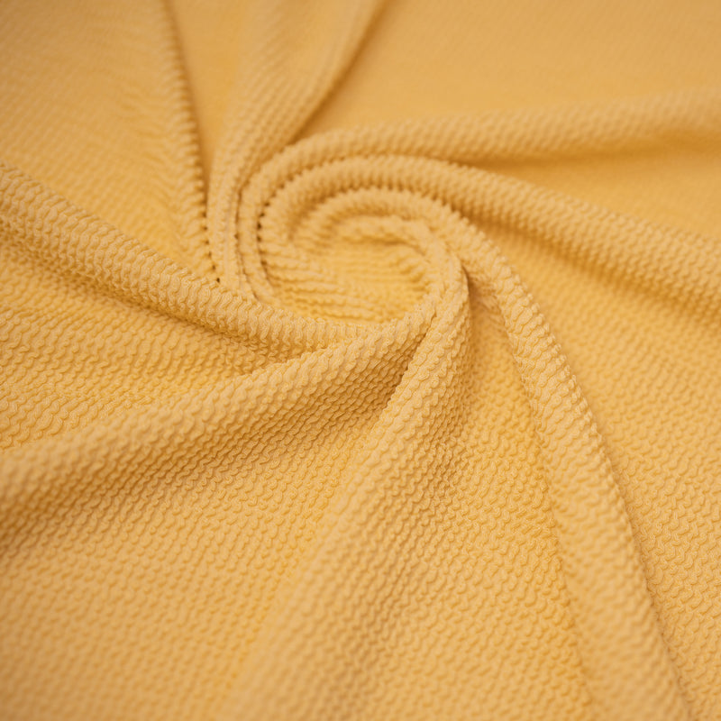 A swirled sample of popcorn polyester spandex jacquard in the color Toasted Coconut.
