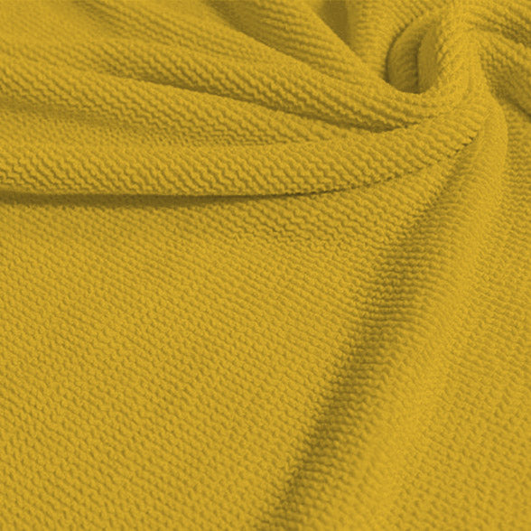 A swirled sample of popcorn polyester spandex jacquard in the color aurora yellow.
