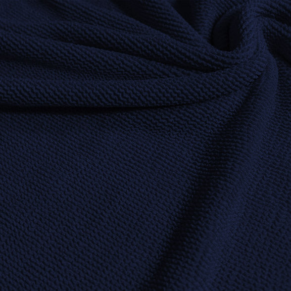 A swirled sample of popcorn polyester spandex jacquard in the color denim blue.