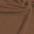 A swirled sample of popcorn polyester spandex jacquard in the color fawn.