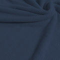 A swirled sample of popcorn polyester spandex jacquard in the color jean blue.
