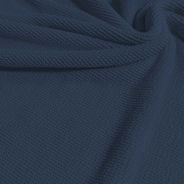 A swirled sample of popcorn polyester spandex jacquard in the color jean blue.