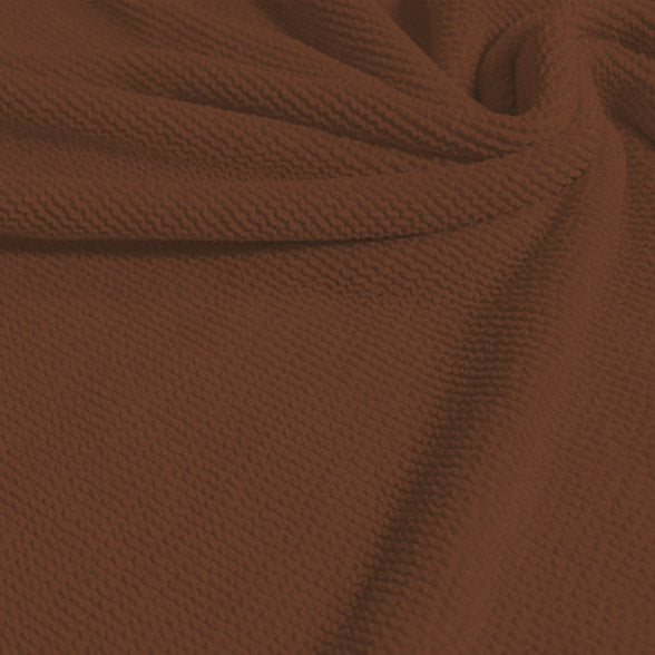 A swirled sample of popcorn polyester spandex jacquard in the color sweet syrup.
