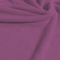 A swirled sample of popcorn polyester spandex jacquard in the color wild orchid pink-purple.