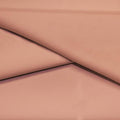 A folded piece of Ripple Recycled Polyester Spandex in the color rosy peach.