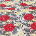 A flat sample of rose and vine embroiered mesh in the colors red-yellow-white.