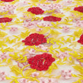 A flat sample of rose and vine embroiered mesh in the colors red-yellow-white.