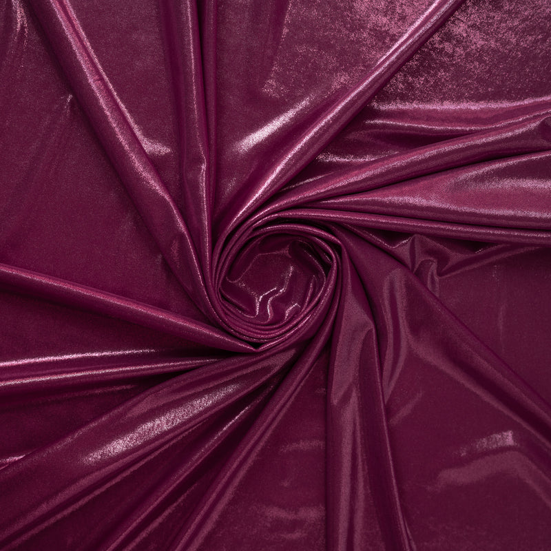 A swirled sample of sheen foiled spandex in the color magenta pink.